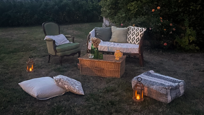 Location pour les événements, mariages et anniversaires d'un salon avec un canapé en rotin et de fauteuil crapaud vert en tissus pour un univers bohème chic