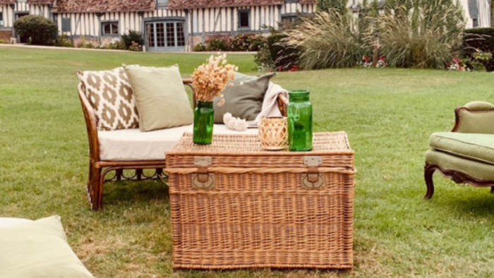 Location pour les événements, mariages et anniversaires d'un salon avec un canapé en rotin et de fauteuil crapaud vert en tissus pour un univers bohème chic