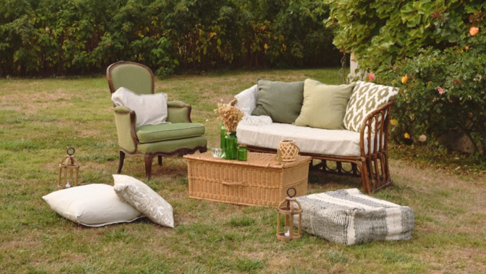 Location pour les événements, mariages et anniversaires d'un salon avec un canapé en rotin et de fauteuil crapaud vert en tissus pour un univers bohème chic