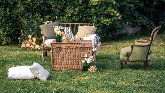 Location pour les événements, mariages et anniversaires d'un salon avec un canapé en rotin et de fauteuil crapaud vert en tissus pour un univers bohème chic