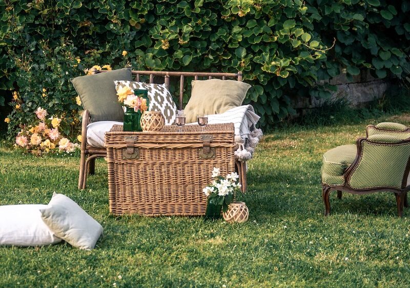 Location pour les événements, mariages et anniversaires d'un salon avec un canapé en rotin et de fauteuil crapaud vert en tissus pour un univers bohème chic