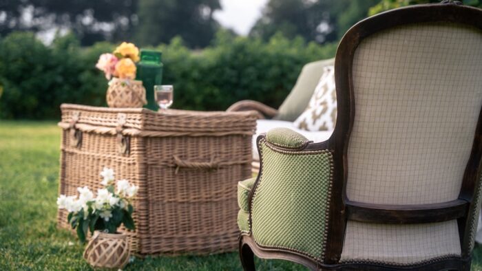 Location pour les événements, mariages et anniversaires d'un salon avec un canapé en rotin et de fauteuil crapaud vert en tissus pour un univers bohème chic