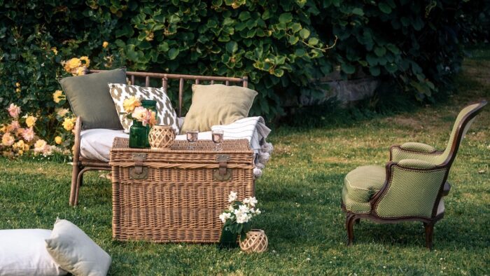 Location pour les événements, mariages et anniversaires d'un salon avec un canapé en rotin et de fauteuil crapaud vert en tissus pour un univers bohème chic