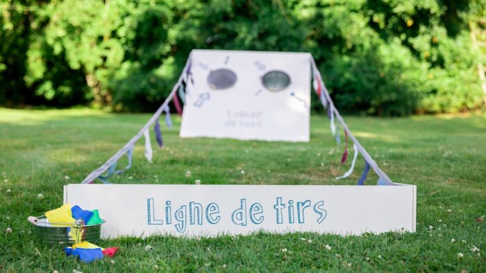 Jeu de lancer de sacs géant en bois avec ligne de départ et drapeau guinguette à louer pour les événements, les mariages, les anniversaires, les soirées, les séminaires