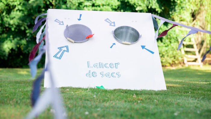 Jeu de lancer de sacs géant en bois avec ligne de départ et drapeau guinguette à louer pour les événements, les mariages, les anniversaires, les soirées, les séminaires